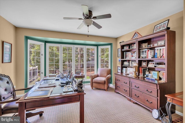 office area featuring ceiling fan, healthy amount of natural light, light colored carpet, and baseboards