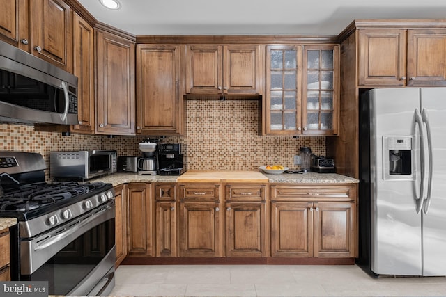 110 Commodore Ct, Philadelphia, PA 19146 - kitchen with appliances with stainless steel finishes, tasteful backsplash, glass insert cabinets, and brown cabinets