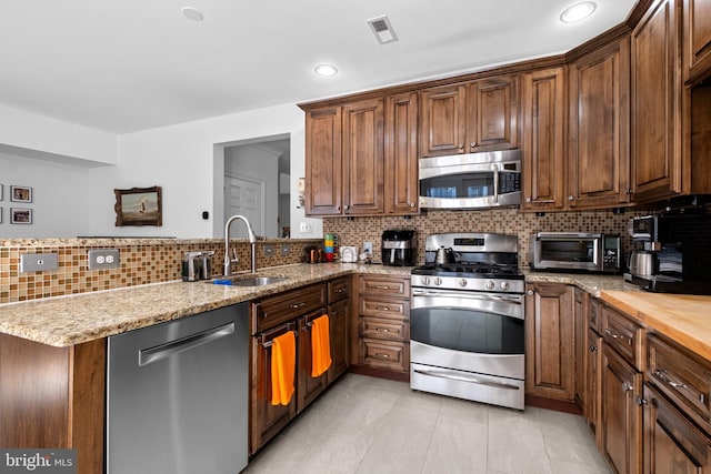 110 Commodore Ct, Philadelphia, PA 19146 - kitchen featuring appliances with stainless steel finishes, a sink, a peninsula, backsplash, and light stone counters