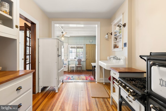 3650 Park Pl NW, Washington, DC 20010 - kitchen featuring a ceiling fan, butcher block countertops, light wood-style flooring, and white cabinets