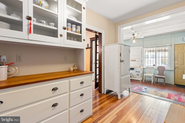 3650 Park Pl NW, Washington, DC 20010 - kitchen featuring light wood finished floors, white cabinets, a ceiling fan, glass insert cabinets, and wood counters
