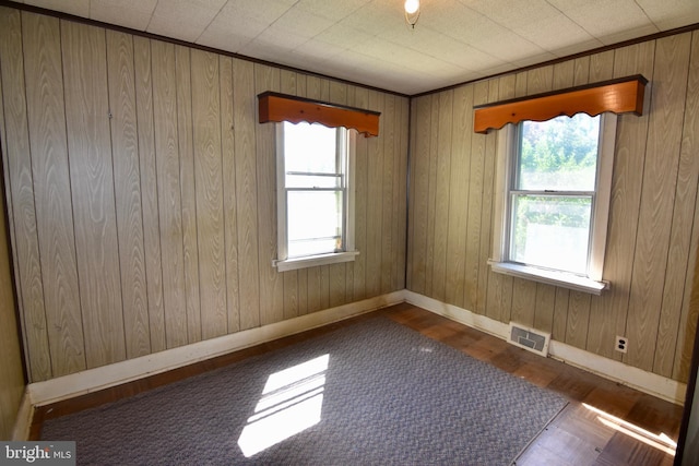 empty room with baseboards, wood finished floors, and wooden walls