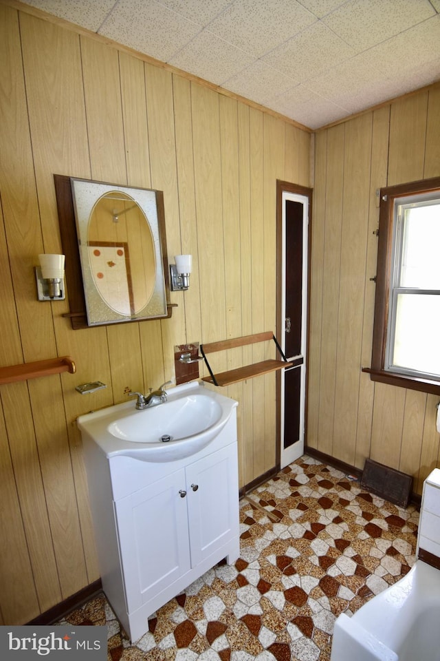 bathroom with tile patterned floors, vanity, wood walls, and baseboards