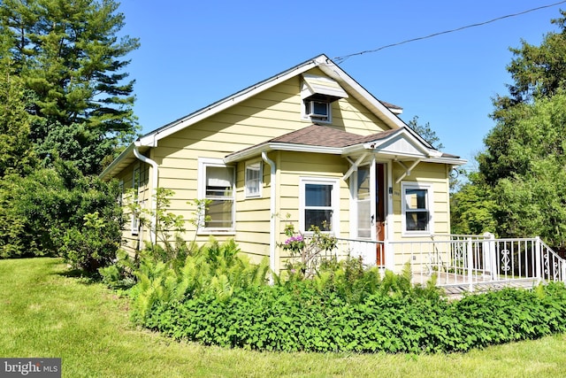 view of front of home with roof with shingles and a front yard