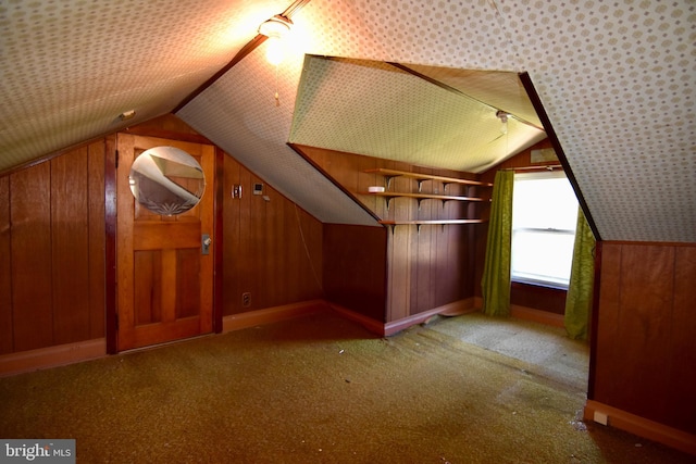 additional living space featuring lofted ceiling, wood walls, and carpet