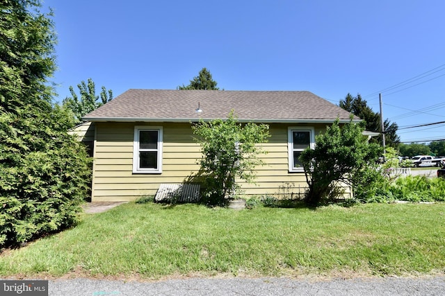 back of property with a lawn and roof with shingles