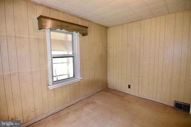 carpeted empty room with wood walls