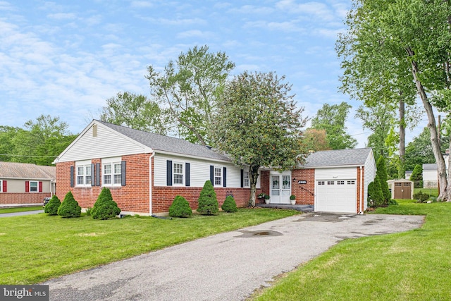 view of front of home featuring brick siding, an attached garage, a shed, asphalt driveway, and a front lawn