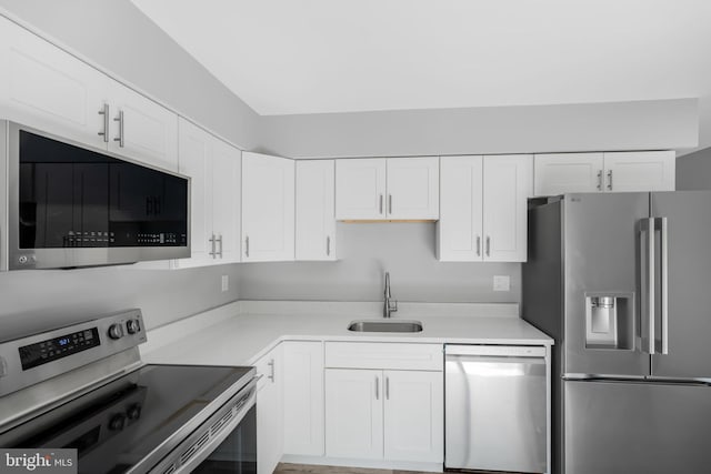 kitchen featuring appliances with stainless steel finishes, a sink, white cabinets, and light countertops