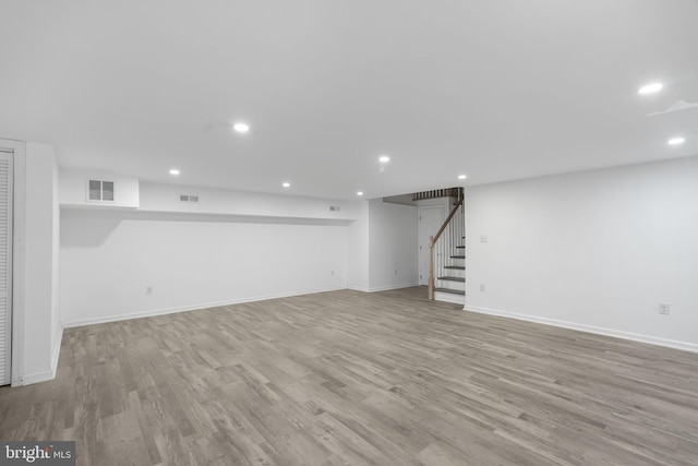 finished below grade area with stairway, light wood finished floors, recessed lighting, and baseboards