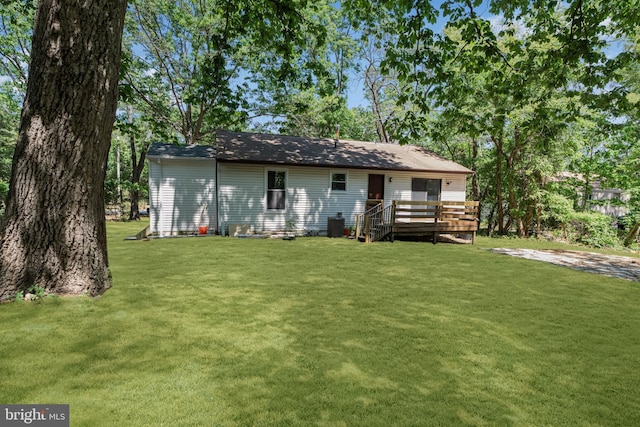 rear view of property with a wooden deck and a yard