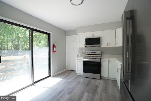 kitchen featuring appliances with stainless steel finishes, light wood-style floors, light countertops, and white cabinets