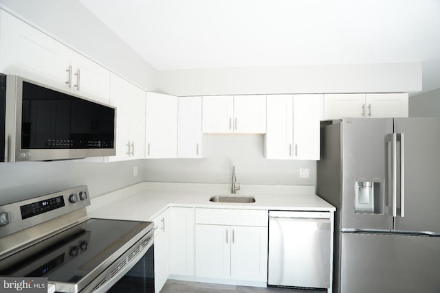 kitchen featuring appliances with stainless steel finishes, a sink, white cabinets, and light countertops