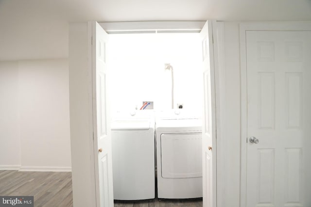laundry area with washer and clothes dryer, wood finished floors, and baseboards