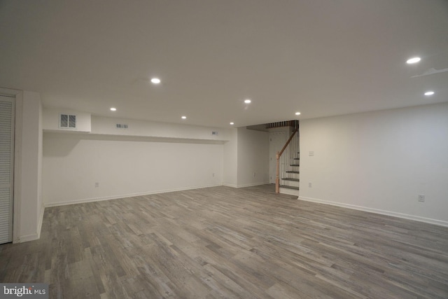finished basement with wood finished floors, stairway, recessed lighting, and baseboards