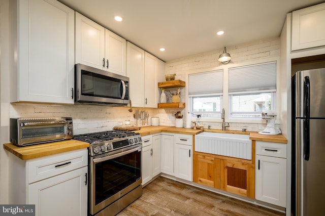 282 Eaton Ave, Hamilton, NJ 08619 - kitchen featuring wood counters, appliances with stainless steel finishes, decorative backsplash, a sink, and light wood-style flooring