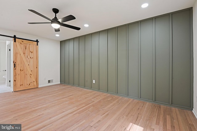 2144 Silentree Dr, Vienna, VA 22182 - unfurnished room featuring light wood-type flooring, a barn door, recessed lighting, a ceiling fan, and a decorative wall