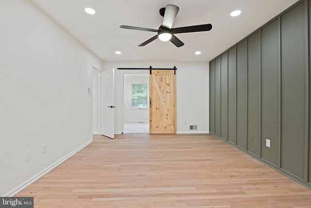 2144 Silentree Dr, Vienna, VA 22182 - empty room featuring a ceiling fan, a barn door, recessed lighting, and light wood-style flooring