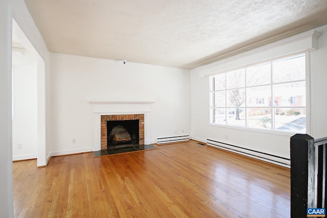 1024 Cottonwood Rd, Charlottesville, VA 22901 - unfurnished living room with baseboard heating, a baseboard radiator, wood finished floors, a brick fireplace, and a textured ceiling