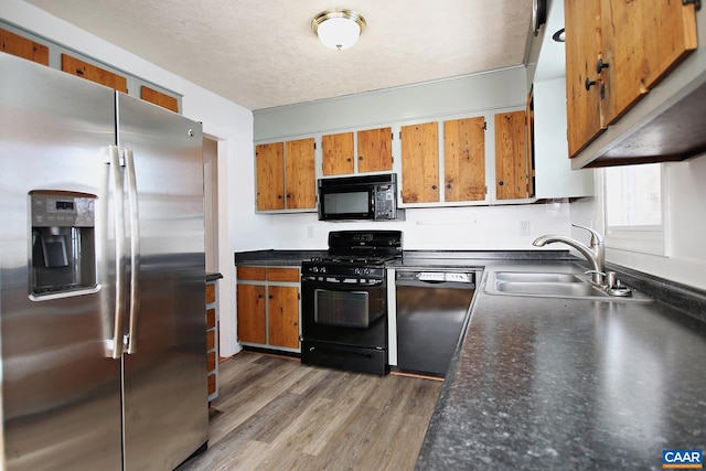 1024 Cottonwood Rd, Charlottesville, VA 22901 - kitchen featuring black appliances, a sink, brown cabinetry, dark countertops, and light wood finished floors