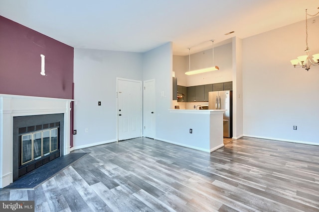 1210 Mist Wood Ct Unit 302, Belcamp, MD 21017 - unfurnished living room featuring a chandelier, high vaulted ceiling, wood finished floors, a glass covered fireplace, and baseboards
