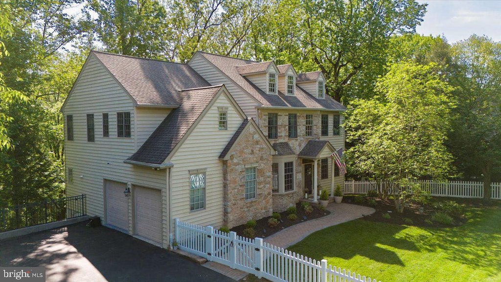 view of front of home with stone siding, asphalt driveway, an attached garage, and roof with shingles