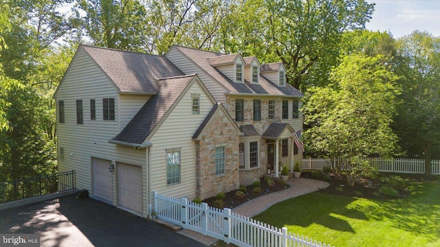 view of front of home with stone siding, asphalt driveway, an attached garage, and roof with shingles