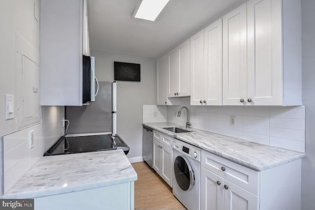 2625 3rd St NE Unit 105, Washington, DC 20002 - kitchen featuring washer / dryer, a sink, decorative backsplash, appliances with stainless steel finishes, and white cabinets