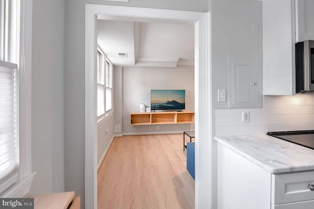 2625 3rd St NE Unit 105, Washington, DC 20002 - kitchen with light wood finished floors, decorative backsplash, stainless steel microwave, white cabinetry, and ornamental molding
