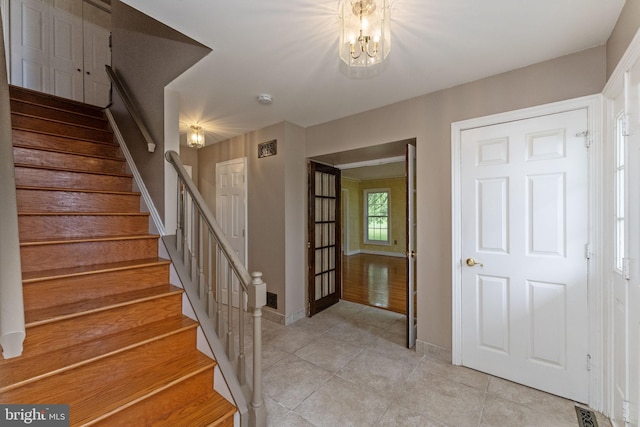 stairway with tile patterned floors, a chandelier, and baseboards