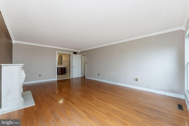 unfurnished living room with light wood-style floors, baseboards, and crown molding
