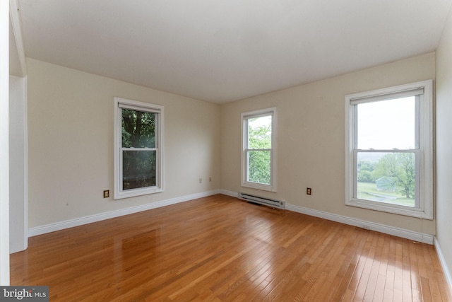 unfurnished room with baseboard heating, baseboards, and light wood finished floors