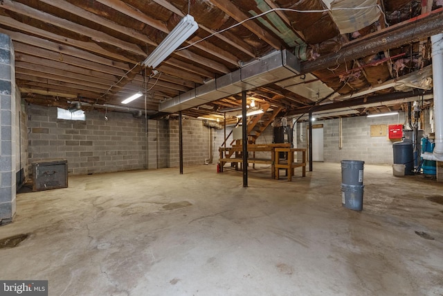 unfinished basement featuring concrete block wall and stairs