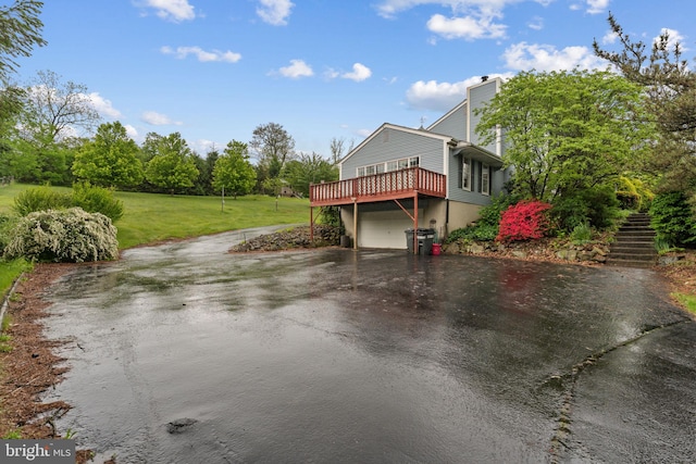 view of home's exterior featuring asphalt driveway, stairs, a chimney, a lawn, and an attached garage