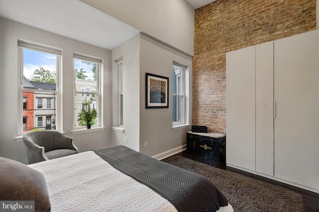 823 11th St NE, Washington, DC 20002 - bedroom with dark wood finished floors, baseboards, brick wall, and a high ceiling