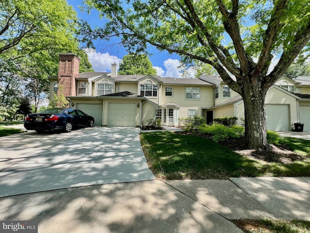 view of front of house featuring concrete driveway, a garage, a front yard, and a chimney