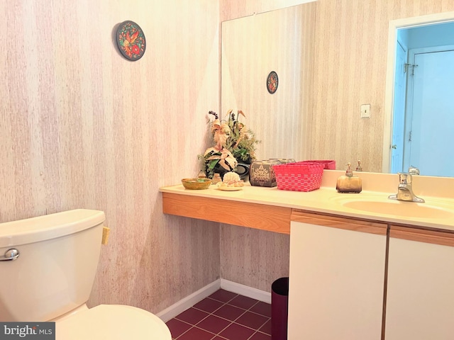 half bathroom featuring tile patterned floors, wallpapered walls, toilet, vanity, and baseboards