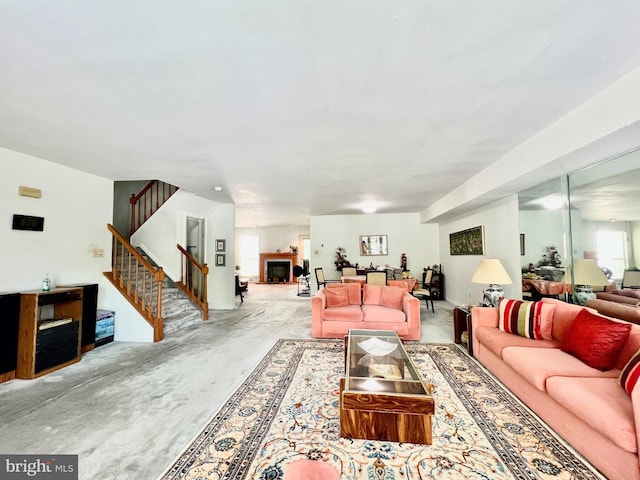 living area featuring concrete flooring, stairs, and a fireplace