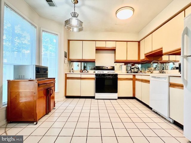 kitchen with white appliances, light countertops, a sink, and pendant lighting