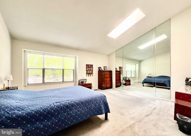bedroom featuring carpet flooring, a skylight, a closet, and lofted ceiling
