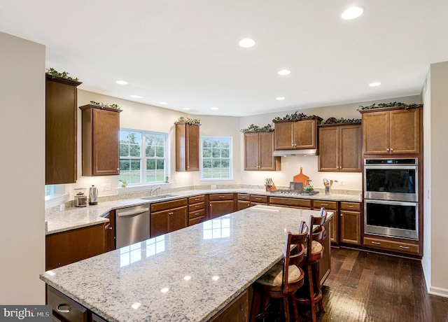 42506 Black Talon Ct, Leesburg, VA 20176 - kitchen featuring appliances with stainless steel finishes, a sink, light stone countertops, dark wood-style floors, and recessed lighting