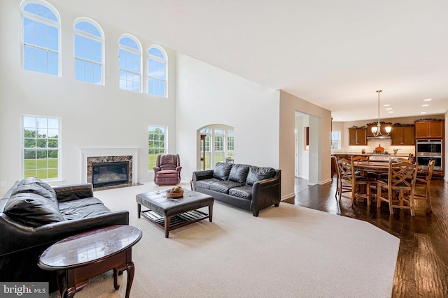 42506 Black Talon Ct, Leesburg, VA 20176 - living room with dark wood-type flooring, a chandelier, a high end fireplace, a high ceiling, and baseboards