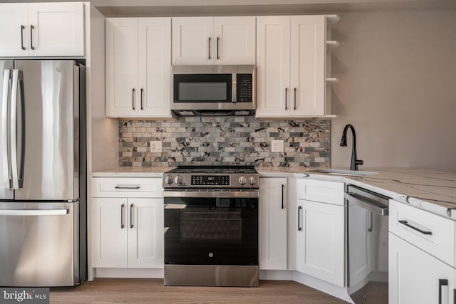 kitchen with appliances with stainless steel finishes, a sink, open shelves, and white cabinetry