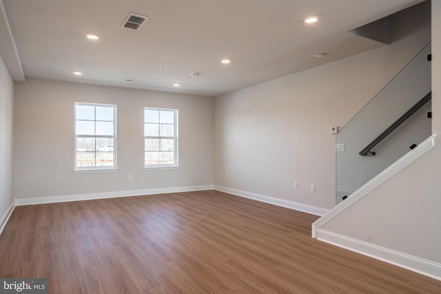 empty room with baseboards, wood finished floors, recessed lighting, and stairs