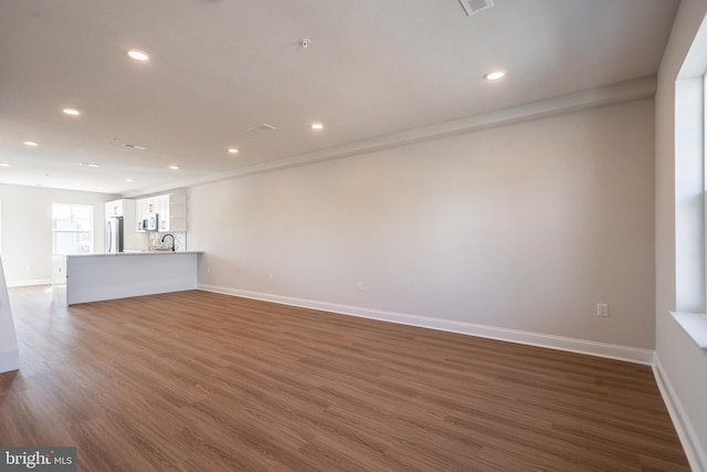 unfurnished living room featuring dark wood finished floors, recessed lighting, and baseboards