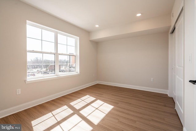 unfurnished bedroom with a closet, wood finished floors, baseboards, and recessed lighting
