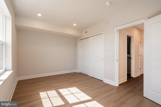 unfurnished bedroom featuring light wood-type flooring, a closet, baseboards, and recessed lighting