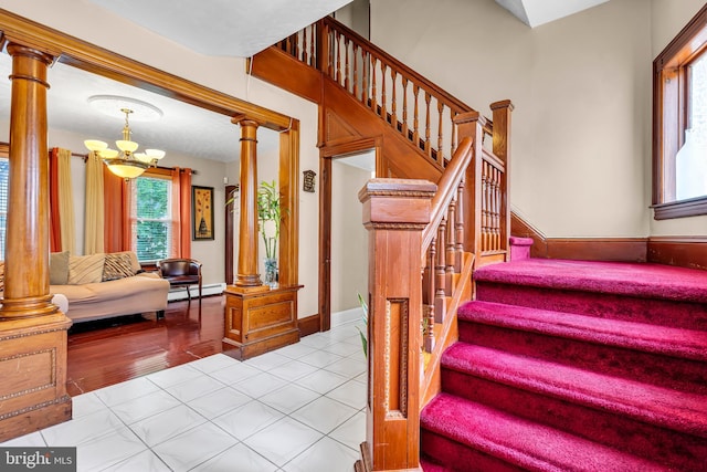 stairway with a baseboard radiator, a chandelier, decorative columns, and tile patterned flooring