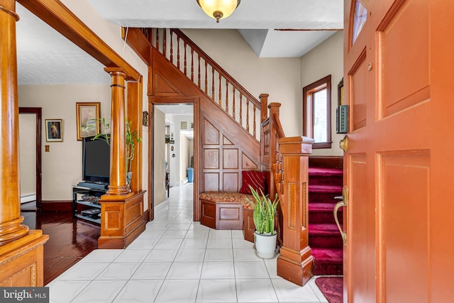 foyer featuring stairs, a baseboard heating unit, and baseboards