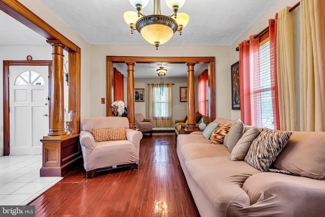 living room with ornate columns, a chandelier, and wood-type flooring